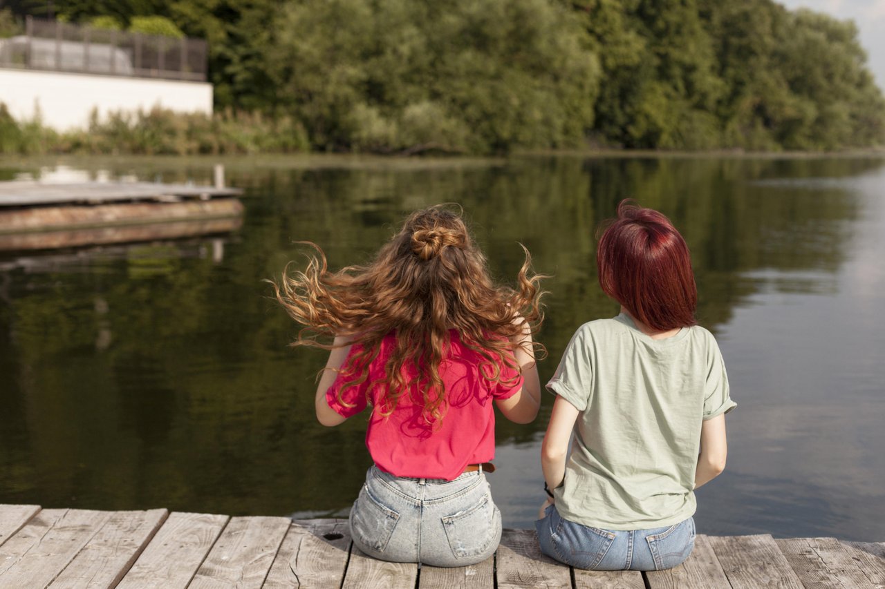 women-staying-dock-looking-lake